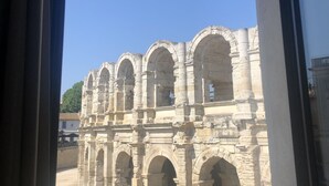 A view of ancient stone arches through a window, with a clear blue sky visible outside. - Opposite Les Arenes and La Major (Arles)