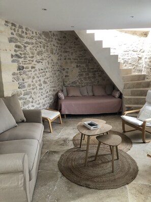 A cozy living area with a stone wall, a sofa, a chair, and a coffee table. - Opposite Les Arenes and La Major (Arles)