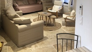 A modern living room with a stone staircase, a sofa, a chair, and a small table. - Opposite Les Arenes and La Major (Arles)