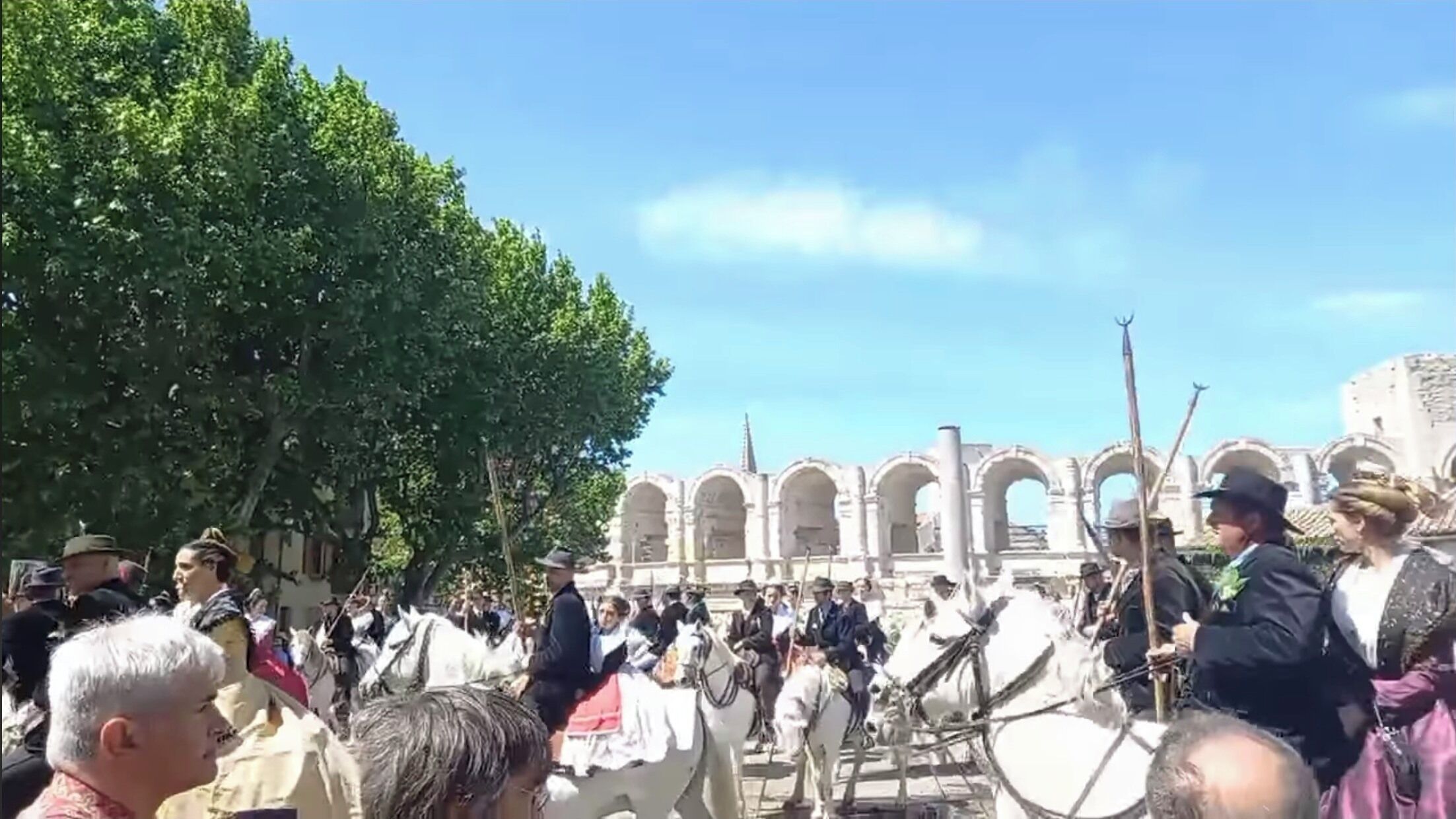 A historical building with arches and columns, surrounded by a crowd of people and horses.