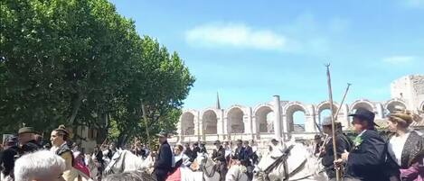 A historical building with arches and columns, surrounded by a crowd of people and horses.
