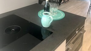 A modern kitchen with a black countertop, a teal vase, and a bottle of champagne.