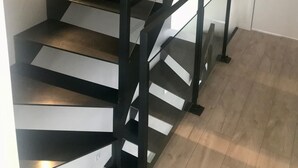 A modern staircase with glass railings and a wooden floor.