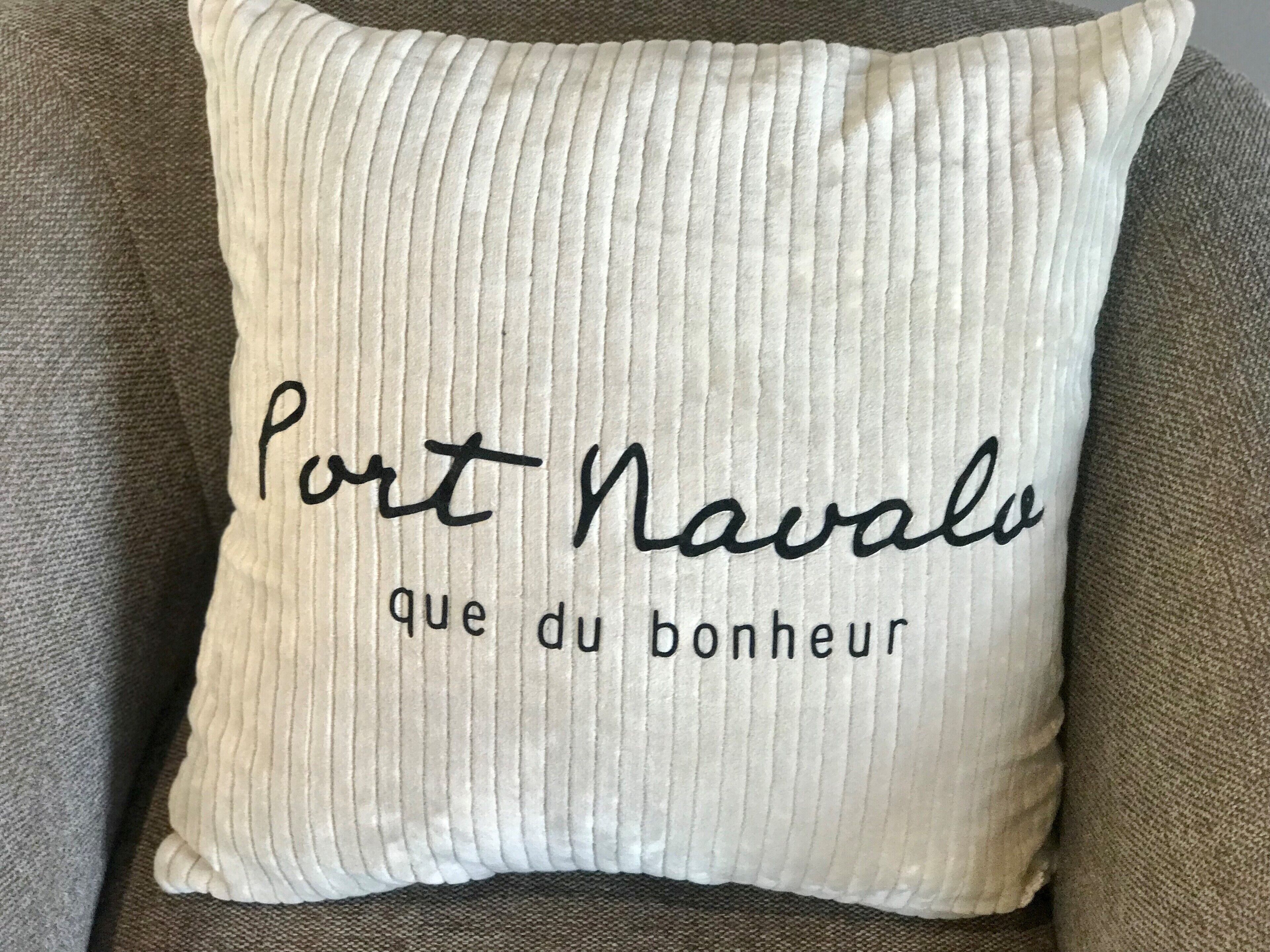 A pillow with the text "Port Navals que du bonheur" on it.