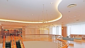 A modern hotel lobby with a curved staircase, a reception desk, and a seating area with tables and chairs. - Chisun Hotel Yokohama Isezakicho (Yokohama)