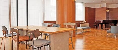 A modern conference room with a wooden table, chairs, and a piano.