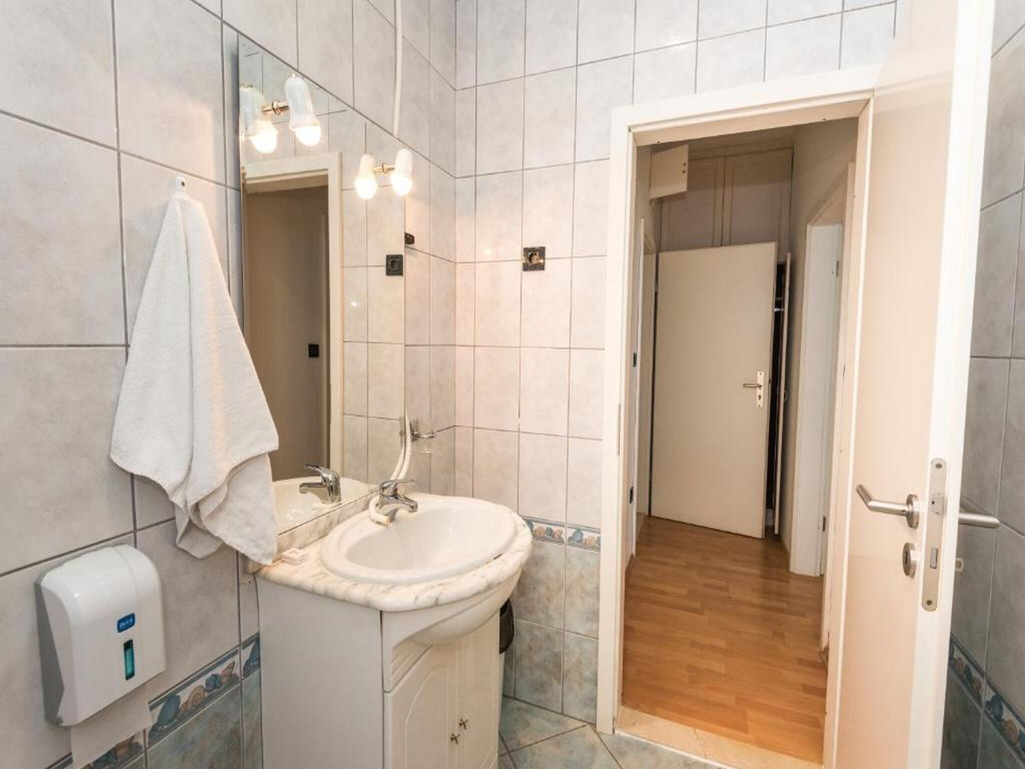 A bathroom with a sink, mirror, towel, and hand dryer.