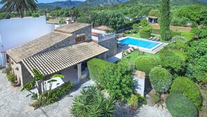Une villa avec piscine, entourée d’une végétation luxuriante et avec des montagnes en toile de fond.