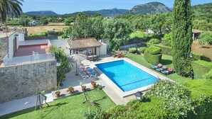 Une piscine entourée d’un jardin bien entretenu, avec une vue sur les montagnes en arrière-plan.