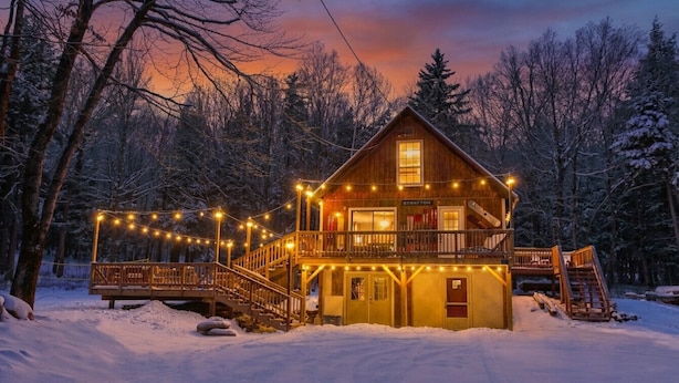 A wooden cabin with a balcony, surrounded by snow-covered trees. - Dream Stratton Forest Cabin w/Hot Tub & Fast WiFi (Stratton)