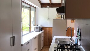 A modern kitchen with white cabinets, a wooden floor, a built-in stove, and a window providing natural light. - Cozy vacation bungalow with breathtaking lake view (Tignale)