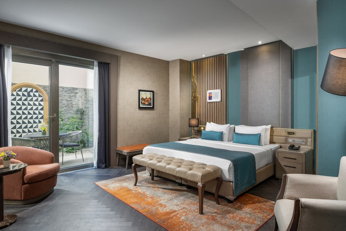 Une chambre d’hôtel moderne avec un grand lit, une banquette, un bureau et une chaise.