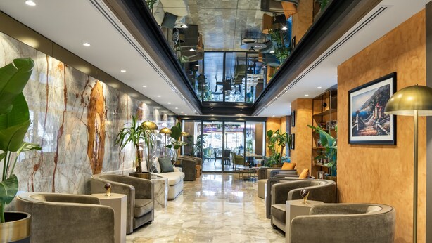 Un hall d’entrée moderne avec un mur de marbre, un espace salon et une mezzanine offrant une vue sur la ville.