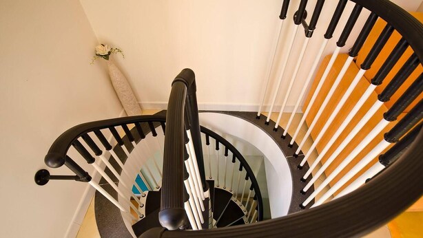 Kierreportaat, joissa on mustat ja valkoiset kaiteet, käsinoja ja matolla päällystetty lattia.
