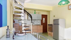 A modern kitchen with a spiral staircase, a dining table with chairs, and a refrigerator. - Sicily new Apartment Next sea With two Bedrooms (Acireale)