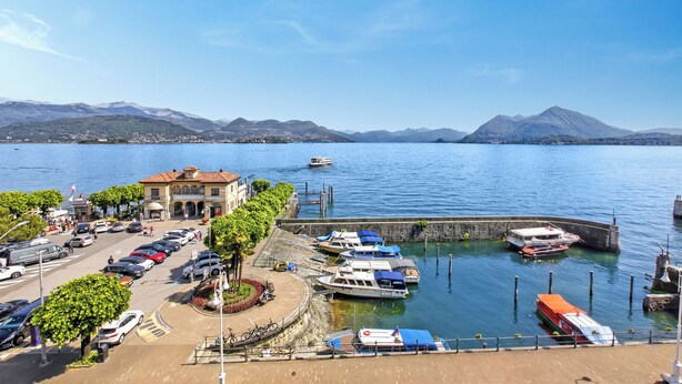 A marina with boats docked, a parking area, and a building with a red roof. - Rooftop - AC, Lake View With Terrace (Stresa)