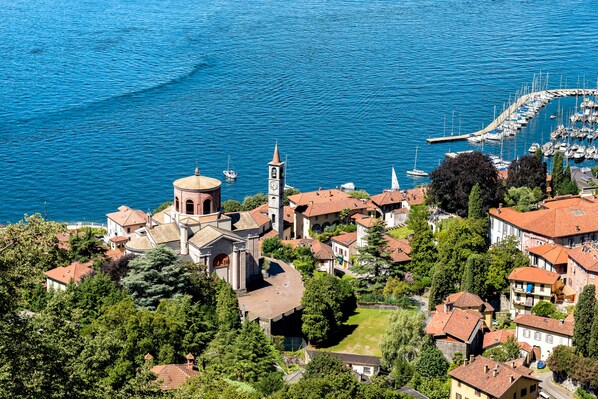 A coastal town with a prominent church, marina, and residential buildings. - Rooftop On Stresa Lake View (Stresa)