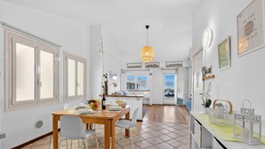 A dining area with a wooden table, chairs, and a view of the kitchen. - Rooftop - AC, Lake View With Terrace (Stresa)