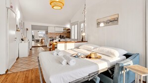 A modern hotel room with a bed, bedside table, and a view into the kitchen area. - Rooftop - AC, Lake View With Terrace (Stresa)