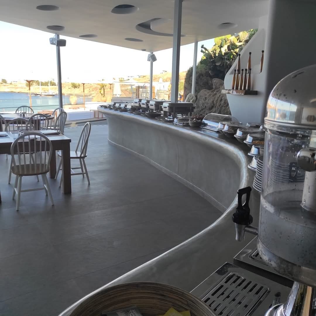A bar area with a view of the sea, outdoor seating, and a grill station.