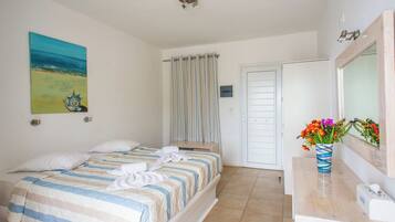 Une chambre à coucher avec un lit, une salle de bain avec un miroir et un tableau accroché au mur.