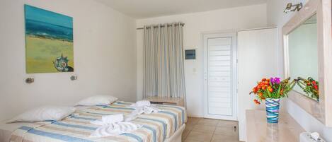Un dormitorio con cama, un baño con espejo y un cuadro en la pared.