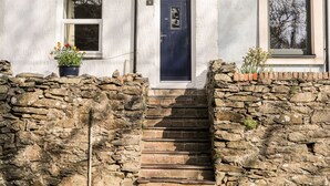 A two-story building with a stone staircase leading to a dark blue door marked with the number 9. - 9 Ty Du Road (Caernarfon)