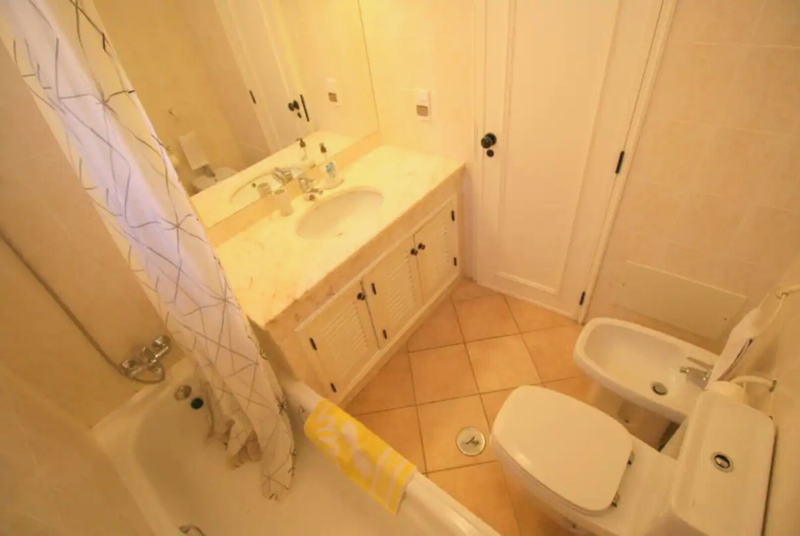 A bathroom with a sink, toilet, and bidet.