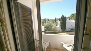 En balkong med utsikt över ett bostadsområde, en vit stol och en stängd dörr.