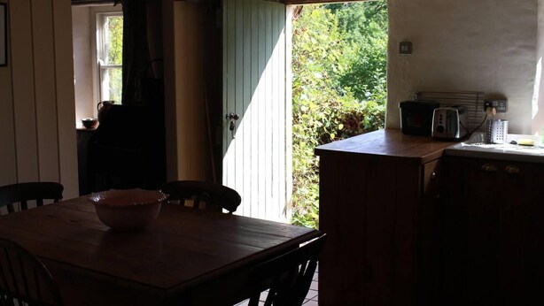 Une cuisine avec une table en bois, des chaises, un four à micro-ondes et un grille-pain.