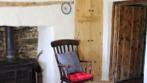Une pièce rustique avec une chaise en bois, un poêle noir et une porte en bois.