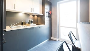 Una cocina moderna con gabinetes grises, electrodomésticos de acero inoxidable y un ventanal que proporciona luz natural.