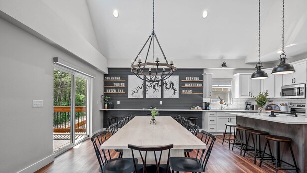 Una cucina moderna con un'ampia isola, pavimento in legno e luci a sospensione.