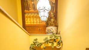 A staircase with a wooden handrail, a small shop at the bottom, and a shelf with books and decorative items above. - Alloggio dei Vassalli, In the Heart of the Historic Center (Naples)