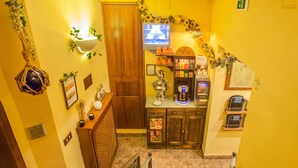 A narrow corridor with a wooden door, a coffee machine, and a shelf with various items. - Alloggio dei Vassalli, In the Heart of the Historic Center (Naples)