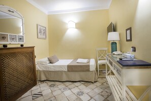 A small, neatly arranged bedroom with a bed, bedside table, lamp, and a desk with a laptop. - Alloggio dei Vassalli, In the Heart of the Historic Center (Naples)