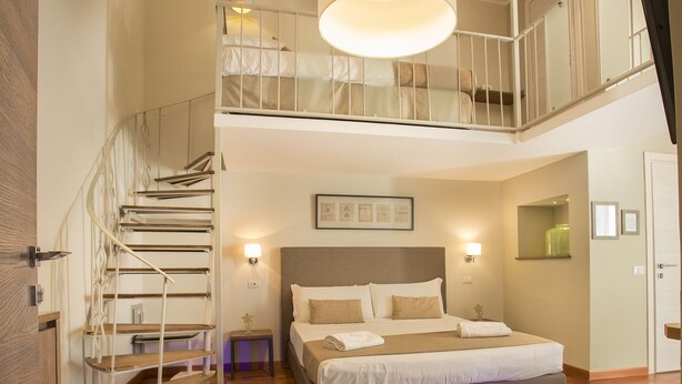 A bedroom with a large bed, a staircase, and a view of the upper floor. - Palazzo Depretis Naples (Naples)