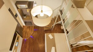 A bunk bed room with a wooden floor, a hanging light fixture, and a small desk with a chair. - Palazzo Depretis Naples (Naples)