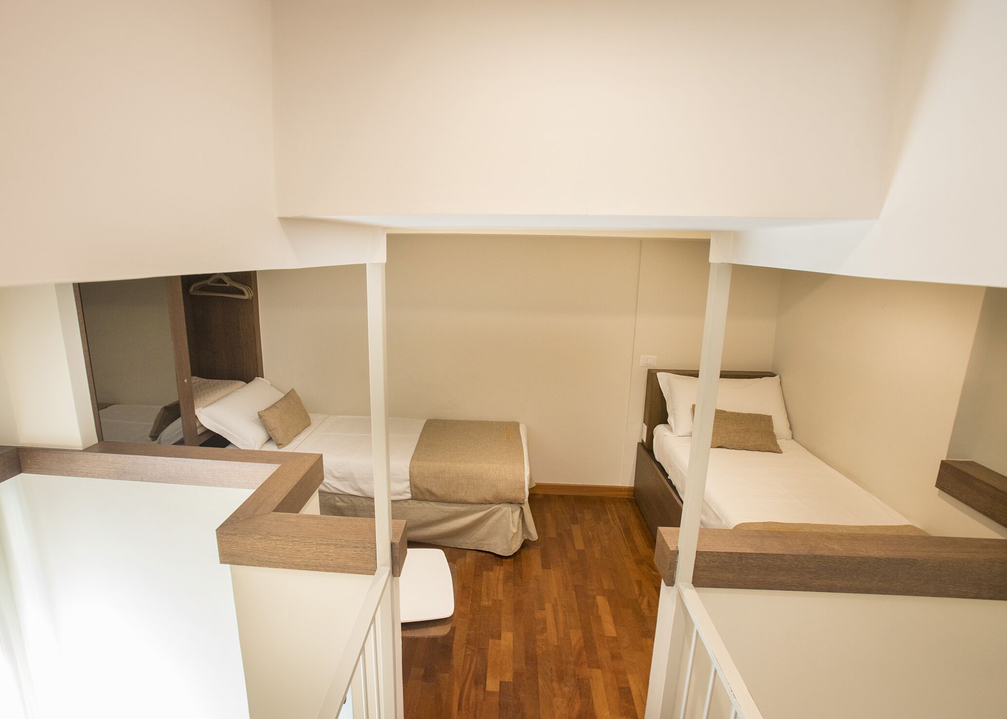 A compact room with bunk beds, wooden flooring, and a simple, clean design.