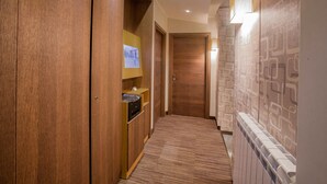 Un couloir avec des portes en bois, un sol recouvert de moquette et un mur orné de motifs.