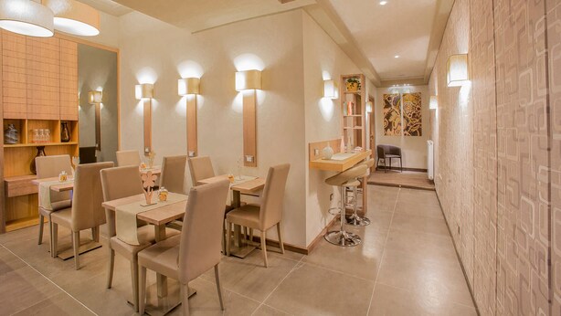 Un espace repas moderne, doté de tables et de chaises, d’un éclairage d’ambiance et d’un mur décoratif.