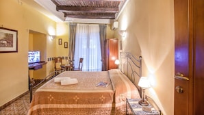 A hotel room with a bed, a desk, a chair, a television, and a door. - Double Triple Room in Naples City Center (Naples)