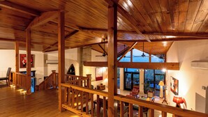 A spacious room with wooden beams, a staircase, and a view of the outdoors. - Tree of Life Junoon in the Hills, Kainchi Dham (Kosiyakutoli)