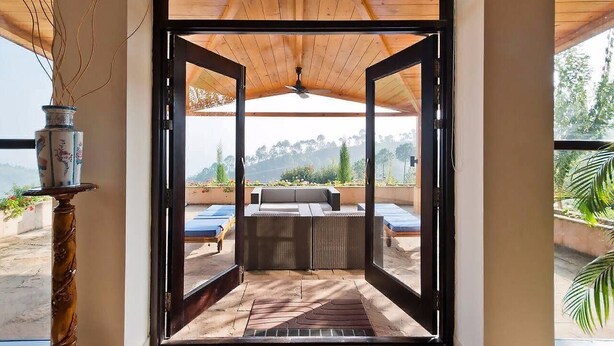 An open patio area with a wooden ceiling, a sofa, and a view of a pool and greenery. - Tree of Life Junoon in the Hills, Kainchi Dham (Kosiyakutoli)