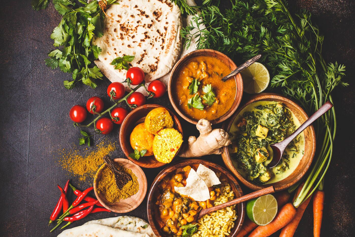 A variety of dishes and ingredients, including flatbreads, a bowl of soup, and fresh vegetables like carrots and tomatoes.