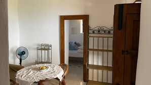 Ein Zimmer mit Holztür, einem Ventilator, einem Tisch mit Korb und einem Stuhl.