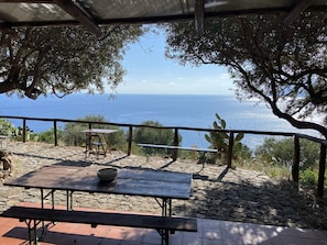 An outdoor seating area with tables and benches overlooking a scenic view of the sea.