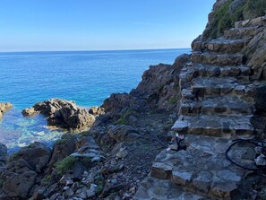 A coastal view with a rocky staircase leading down to the sea.