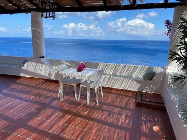 A covered outdoor seating area with a view of the ocean.