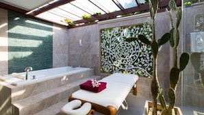 Ein Wellnessraum mit Badewanne, Massagetisch und einer Sukkulente.